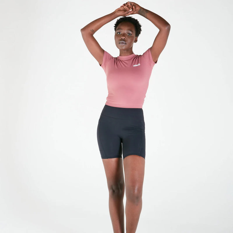 Woman in pink t-shirt and dark V-Back Bike Shorts with pockets raising arms above head